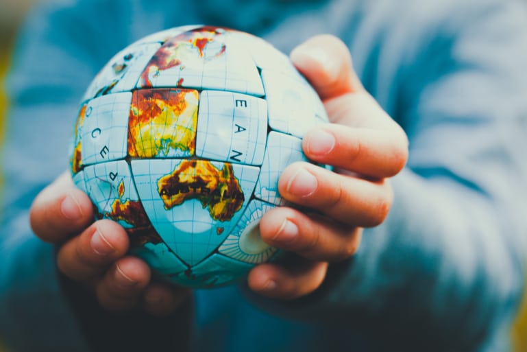 Hands holding a round globe in a Rubik's cube style