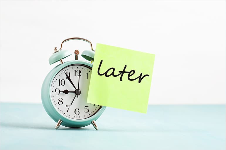 pastel colored analog clock with a bright green post it note attached that says"later"
