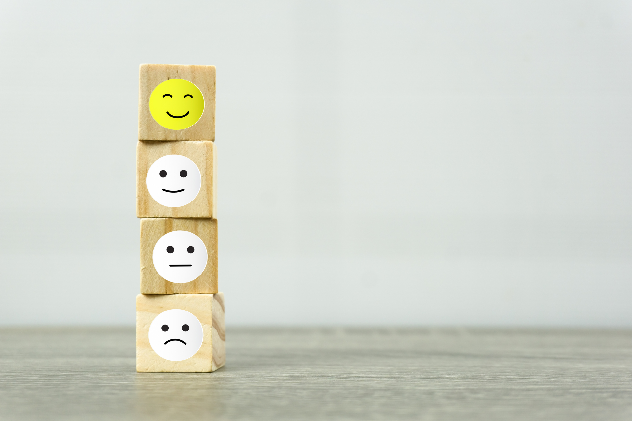 four stacked building blocks with sad to smiley faces