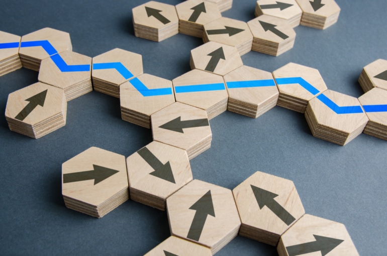 Wooden tiles with an optimal blue path among arrows facing in many directions.