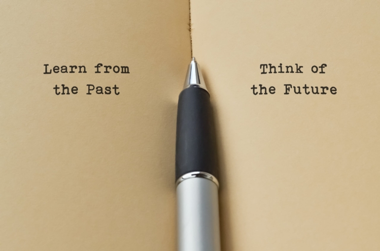 Open book with a pen in the middle. Text on left page reads Learn from the Past. Text on right page reads Think of the Future.