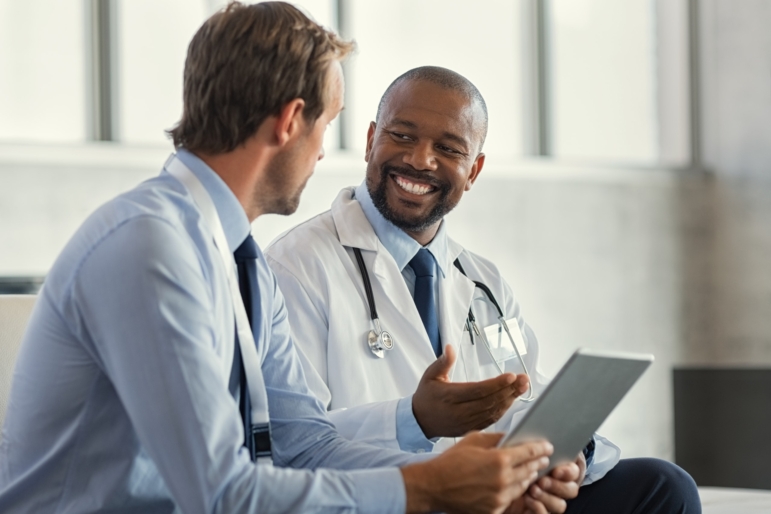 Two doctors sitting down having a discussion about patient diagnosis in a curbside consult.