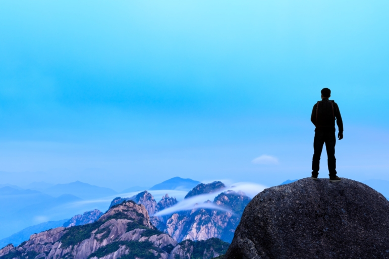 backpacker on top of a mountain enjoying valley view
