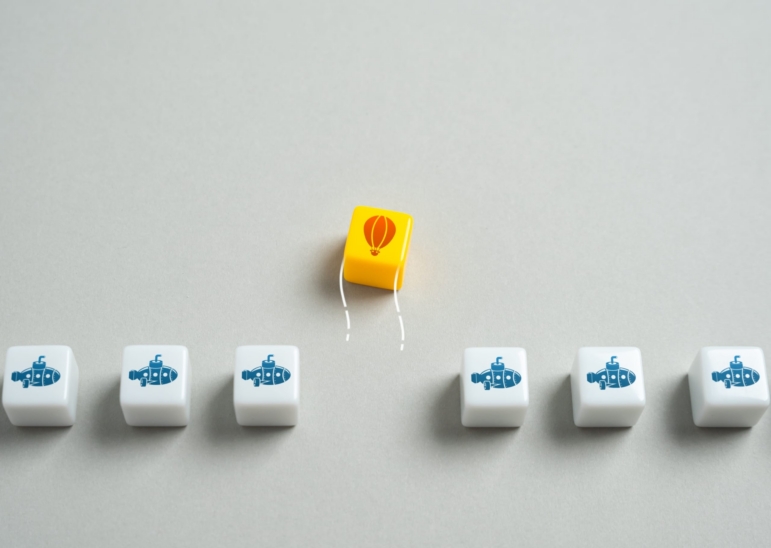 Yellow tile with a hot air balloon rising above identical tiles in a row, symbolizing intentionally projecting oneself toward growth, individuality, and happiness.